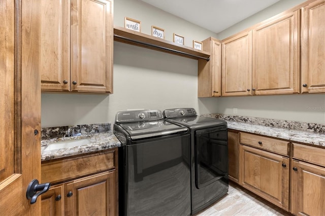 clothes washing area with cabinets, washer and clothes dryer, and sink