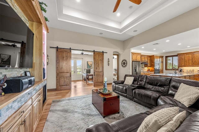 710 Albee Rd W, Nokomis, FL 34275 - living room with a barn door, a ceiling fan, light wood-type flooring, recessed lighting, and a raised ceiling