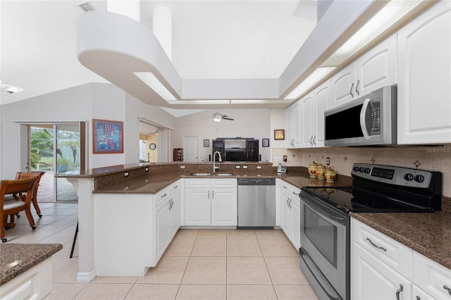 kitchen with kitchen peninsula, stainless steel appliances, white cabinets, and dark stone counters