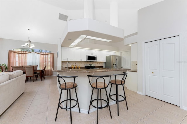 kitchen with white cabinets, a kitchen breakfast bar, light tile patterned floors, and stainless steel appliances