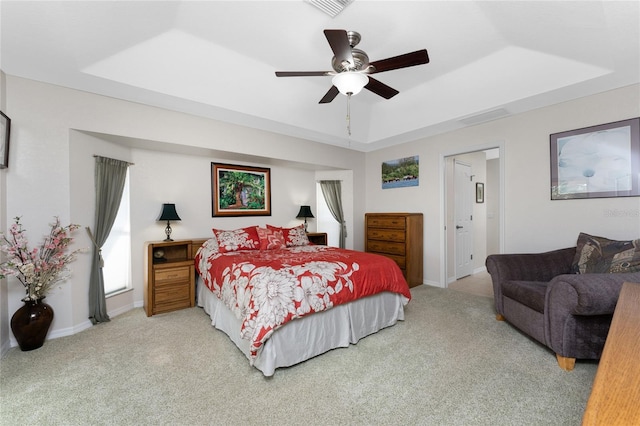 carpeted bedroom featuring ceiling fan and a raised ceiling