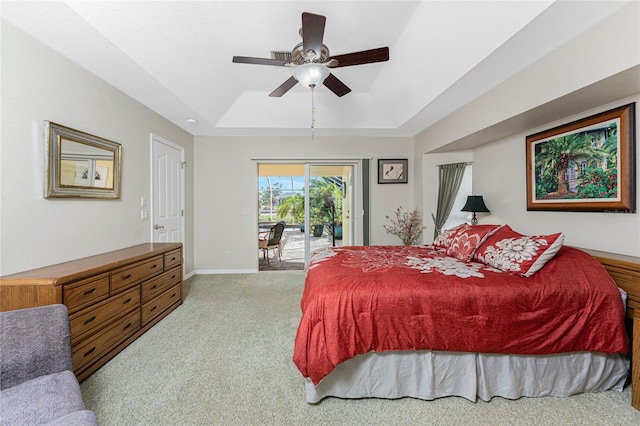 carpeted bedroom with a tray ceiling, access to exterior, and ceiling fan