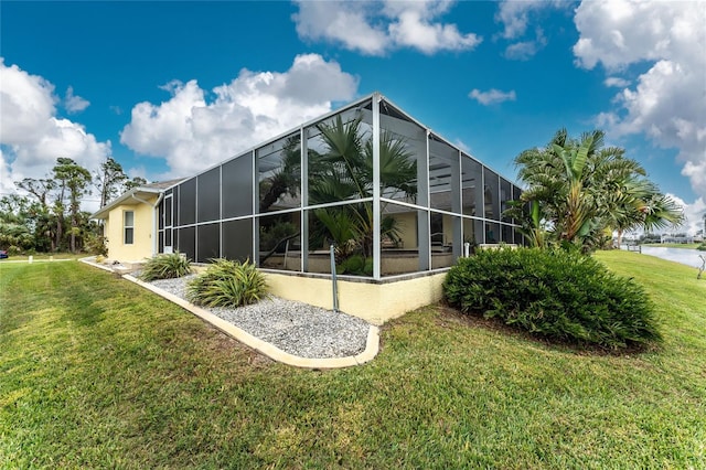 rear view of property with glass enclosure, a yard, and a water view