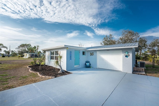 view of front of property featuring central air condition unit, concrete driveway, stucco siding, metal roof, and a garage