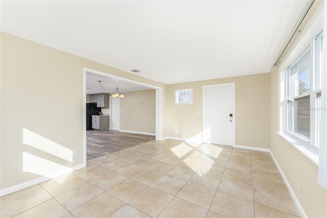 unfurnished room with light tile patterned floors and a chandelier