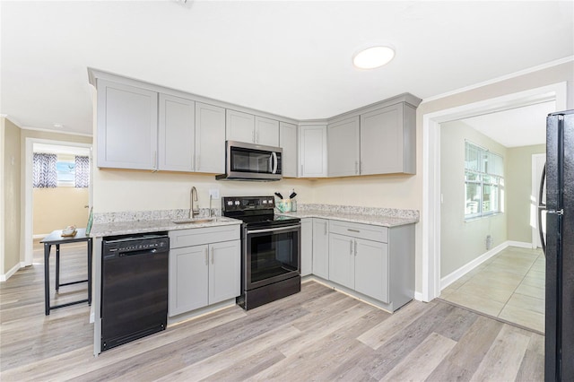 kitchen with sink, gray cabinetry, black appliances, light hardwood / wood-style floors, and light stone countertops