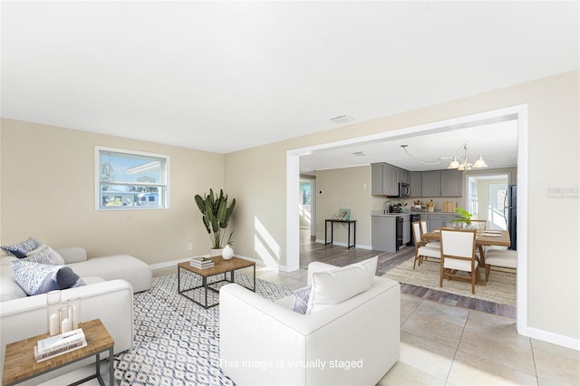 living area featuring visible vents, a chandelier, a wealth of natural light, and light tile patterned flooring