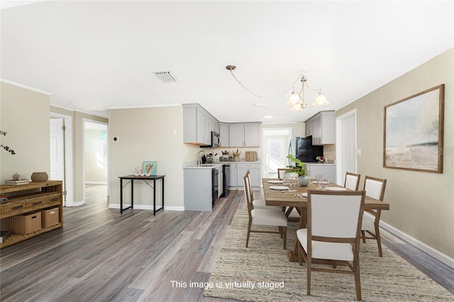 dining space with baseboards, crown molding, visible vents, and wood finished floors