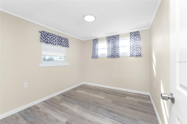 unfurnished room with crown molding, baseboards, and wood finished floors