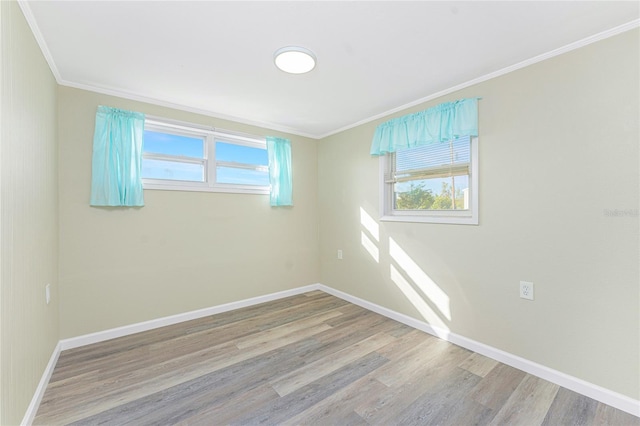 empty room featuring light wood-style floors, baseboards, and crown molding