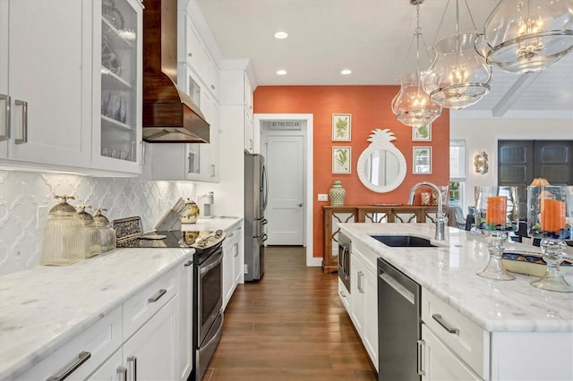 kitchen with sink, custom range hood, appliances with stainless steel finishes, decorative light fixtures, and white cabinetry