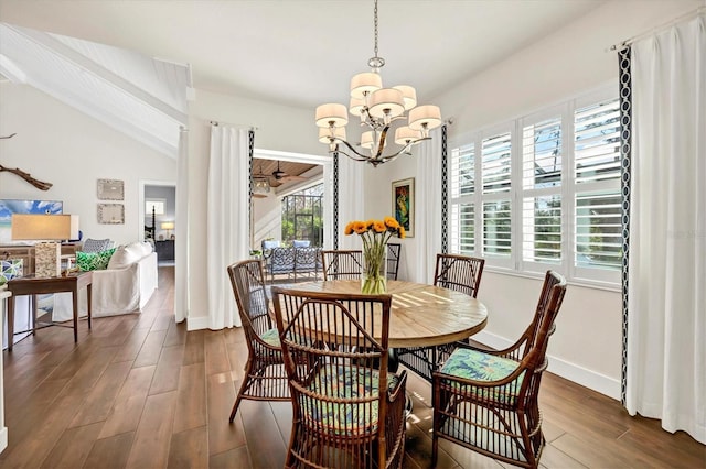 dining space with vaulted ceiling, plenty of natural light, dark hardwood / wood-style floors, and an inviting chandelier