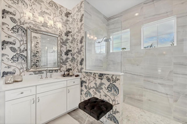 bathroom with a tile shower and vanity