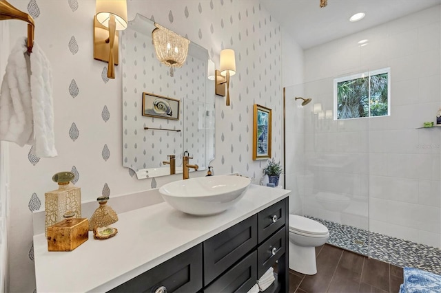 bathroom with tiled shower, vanity, and toilet