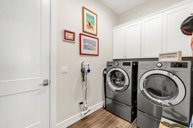 clothes washing area with cabinets and washing machine and clothes dryer