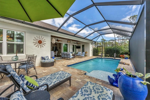 view of swimming pool featuring ceiling fan, an outdoor hangout area, a patio, and glass enclosure