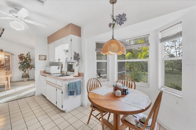 tiled dining space with ceiling fan and sink