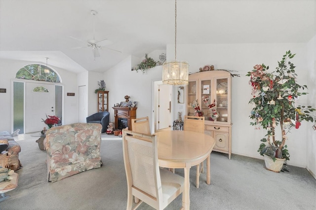 dining area with ceiling fan with notable chandelier, carpet floors, and lofted ceiling