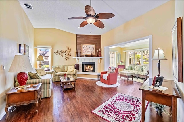 living room with a textured ceiling, vaulted ceiling, ceiling fan, hardwood / wood-style flooring, and a fireplace