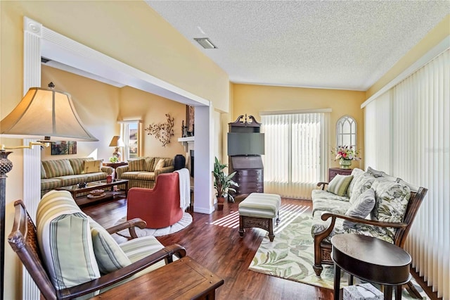 living room featuring dark hardwood / wood-style flooring, a textured ceiling, and lofted ceiling