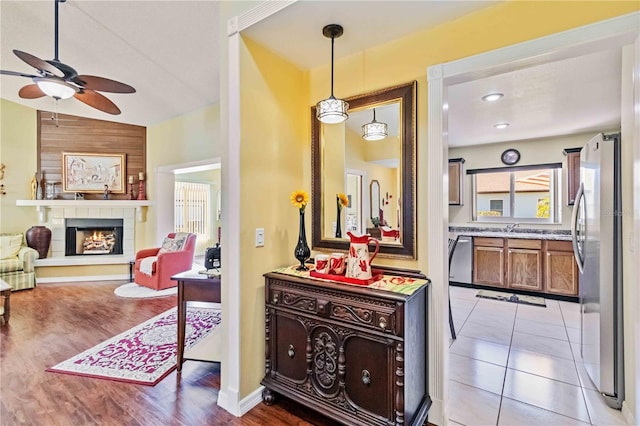 hallway with light tile patterned flooring, sink, and vaulted ceiling