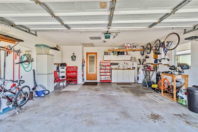 garage with a workshop area, electric water heater, and a garage door opener