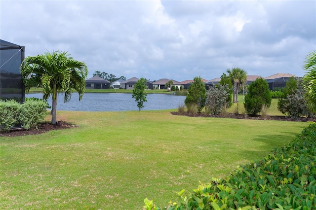 view of yard with a lanai and a water view