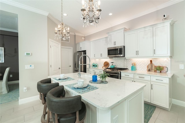 kitchen featuring white cabinets, stainless steel appliances, an inviting chandelier, and an island with sink