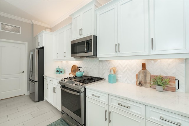 kitchen featuring light stone counters, white cabinetry, ornamental molding, and appliances with stainless steel finishes