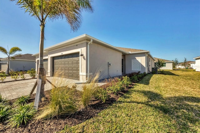 view of home's exterior featuring a garage, a lawn, decorative driveway, and stucco siding