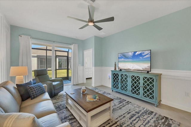 tiled living area featuring ceiling fan and wainscoting