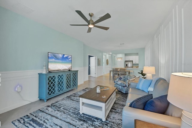 living room with ceiling fan, light tile patterned flooring, and wainscoting