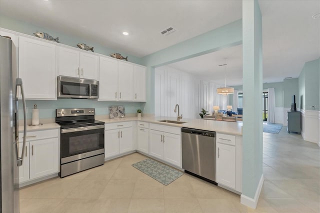 kitchen with a sink, stainless steel appliances, light countertops, and white cabinetry