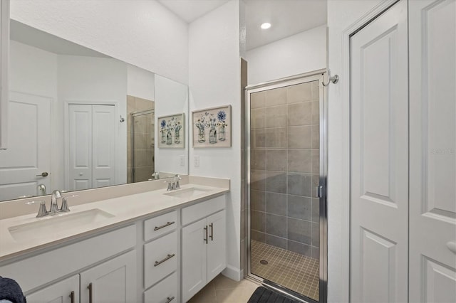 bathroom featuring a sink, a shower stall, double vanity, and a closet