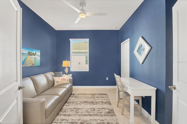 office area with ceiling fan, a textured wall, and baseboards