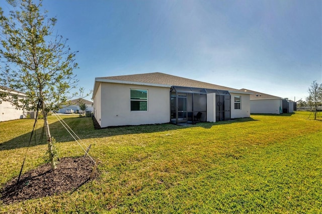 back of property with a lawn and stucco siding