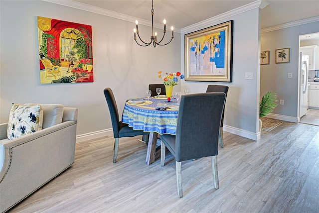 dining area with light hardwood / wood-style flooring, an inviting chandelier, and crown molding