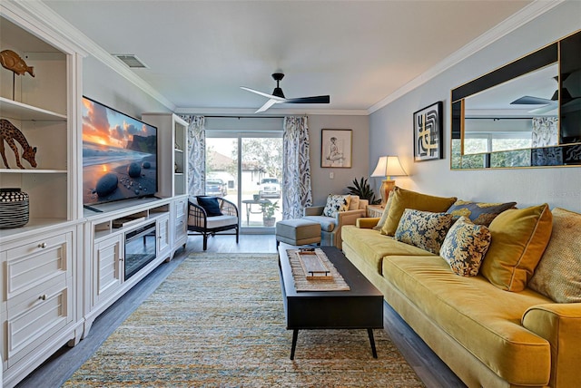 living room with crown molding, ceiling fan, a healthy amount of sunlight, and wood-type flooring