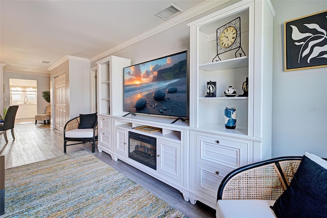 living room featuring dark hardwood / wood-style floors, a fireplace, built in features, and crown molding