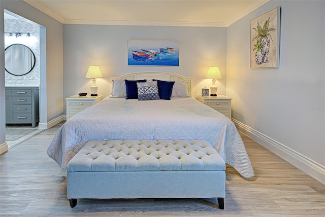 bedroom featuring light hardwood / wood-style floors, ornamental molding, and ensuite bath