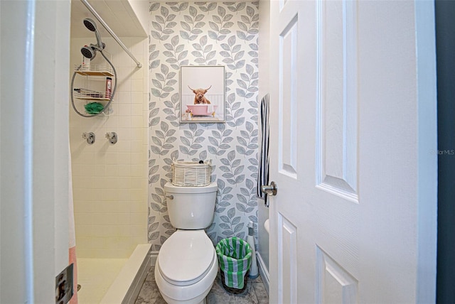 bathroom with a tile shower and toilet