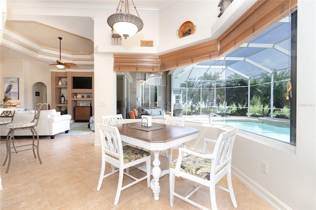 tiled dining area with ceiling fan, crown molding, and built in shelves