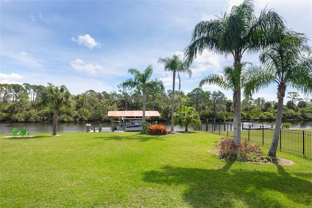 view of yard featuring fence, a dock, and a water view