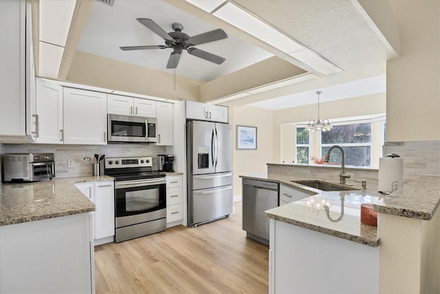 kitchen featuring white cabinets, sink, hanging light fixtures, kitchen peninsula, and stainless steel appliances