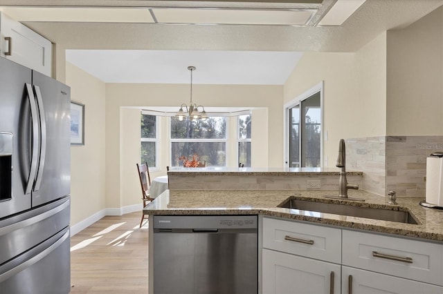 kitchen featuring sink, decorative light fixtures, a notable chandelier, white cabinetry, and stainless steel appliances