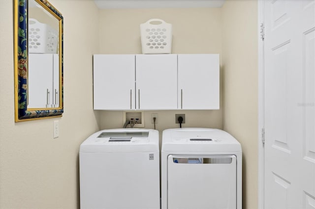 clothes washing area with cabinets and washing machine and clothes dryer