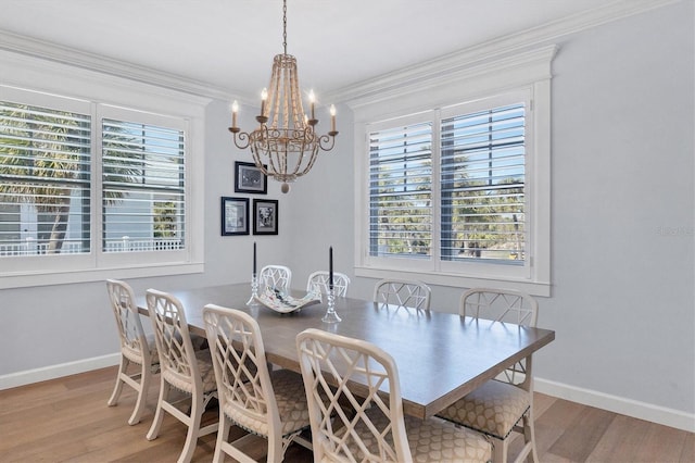 dining space with light hardwood / wood-style floors, an inviting chandelier, and crown molding