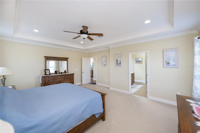 bedroom with ceiling fan, crown molding, a tray ceiling, and ensuite bath