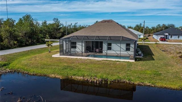 rear view of house with a lanai, a yard, and a water view