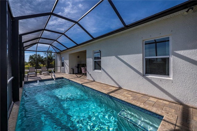 view of swimming pool with glass enclosure, a patio area, area for grilling, and pool water feature